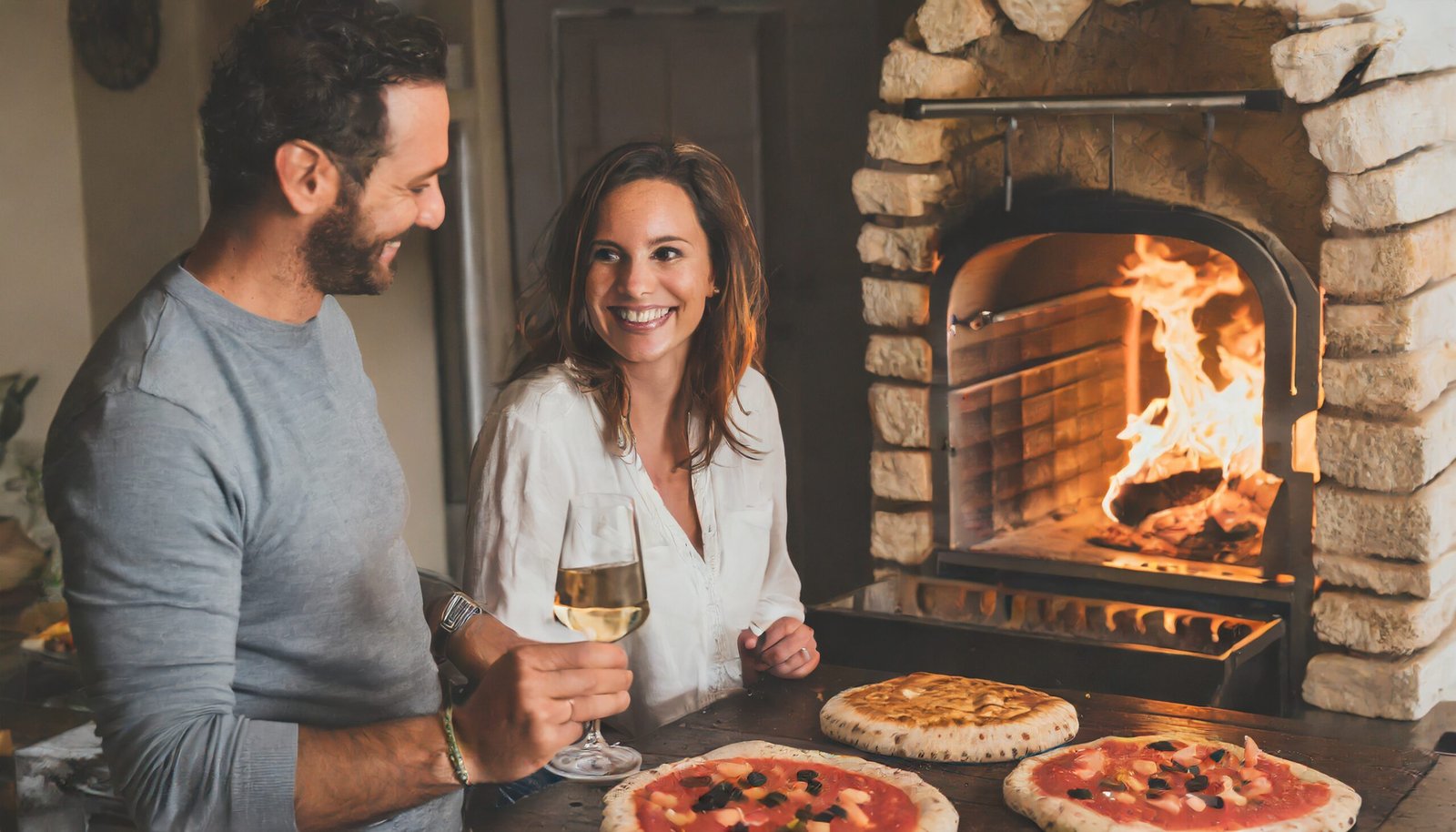 pizza oven and bbq with hardwood logs burning and smiling